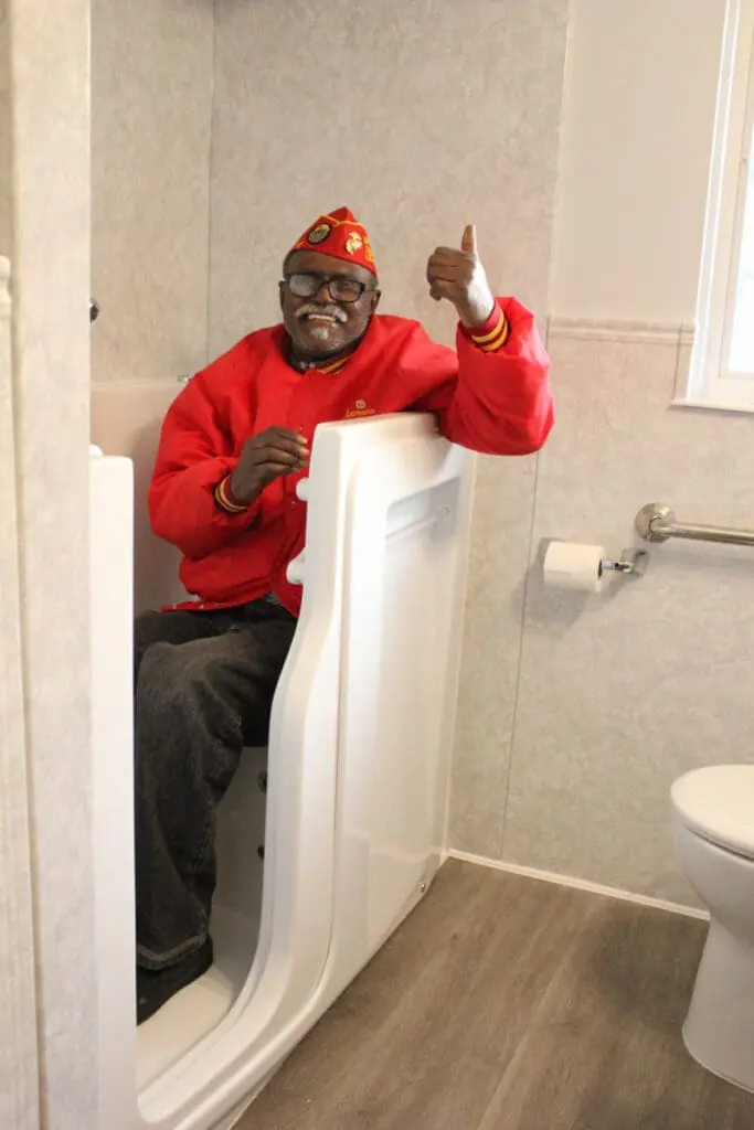 A delighted man in a red shirt enjoying his step-through tub after winning a free bathroom remodel giveaway.