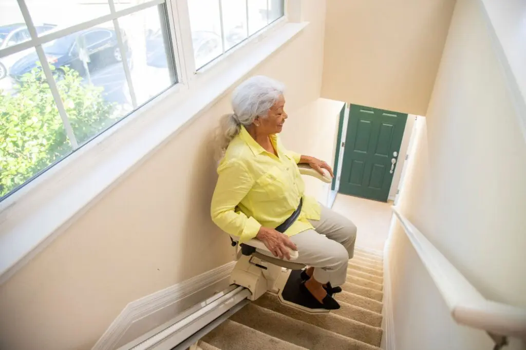 Elderly woman safely descending stairs on a lift.