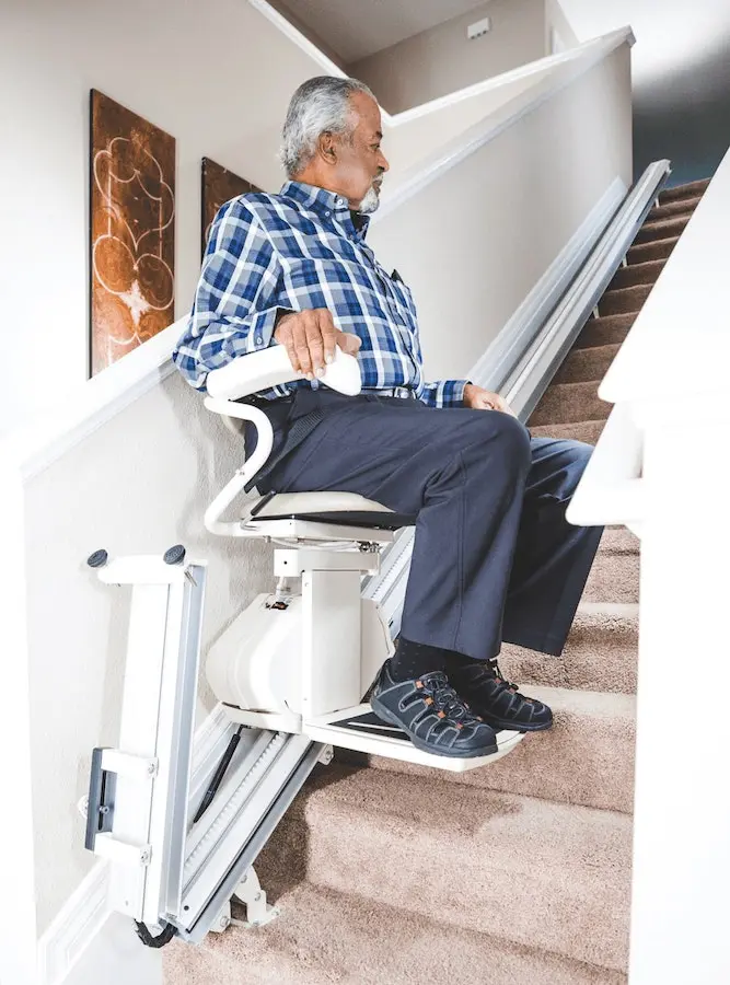 Elderly man sitting comfortably on a stair lift.