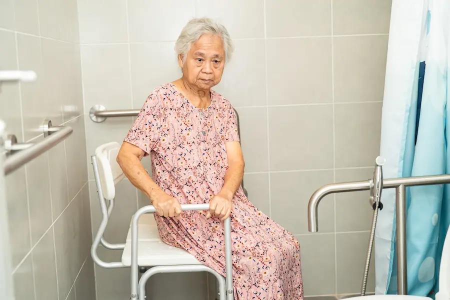 Senior Woman Sitting in Bathroom with Assistance Chair