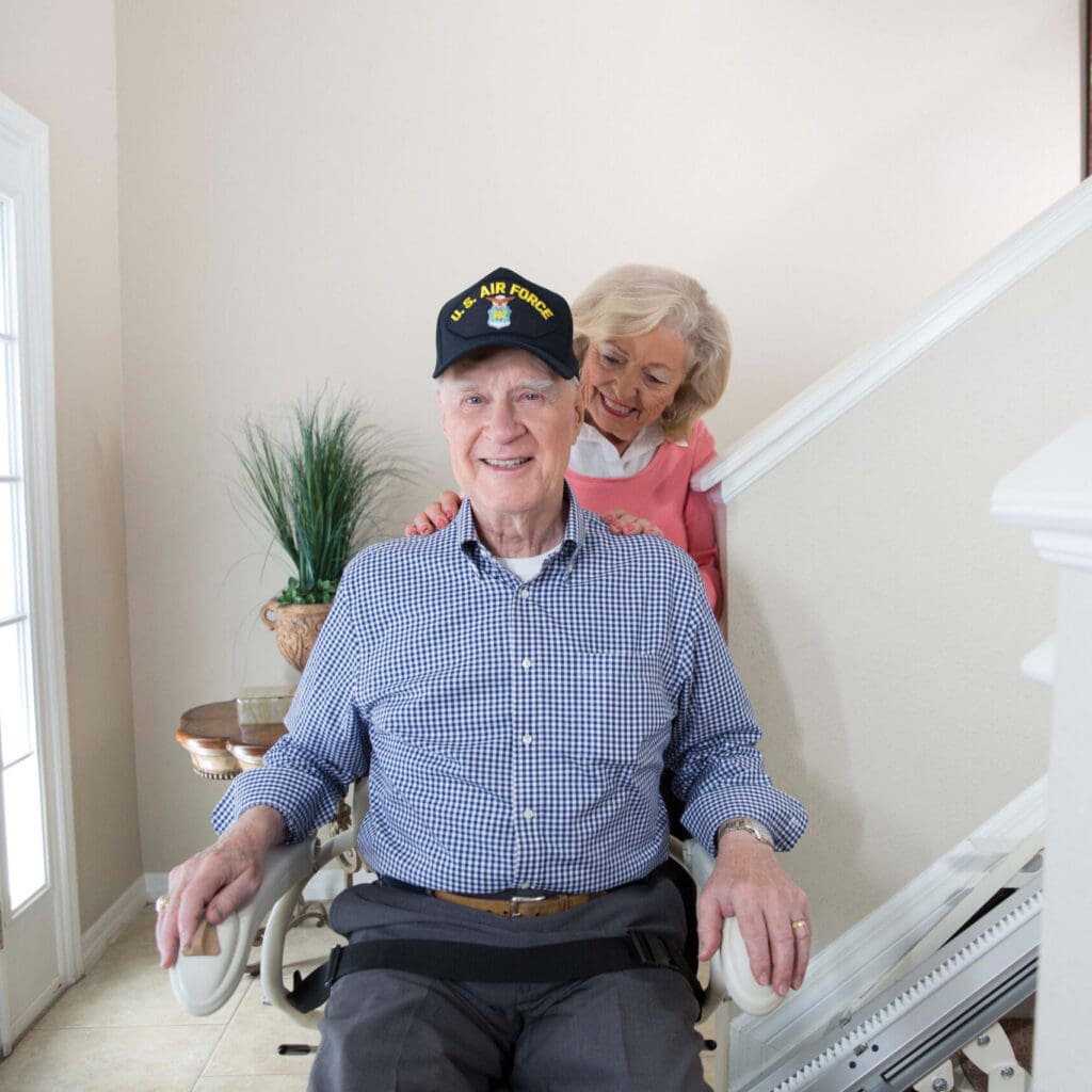 Elderly couple on a stair lift in their home