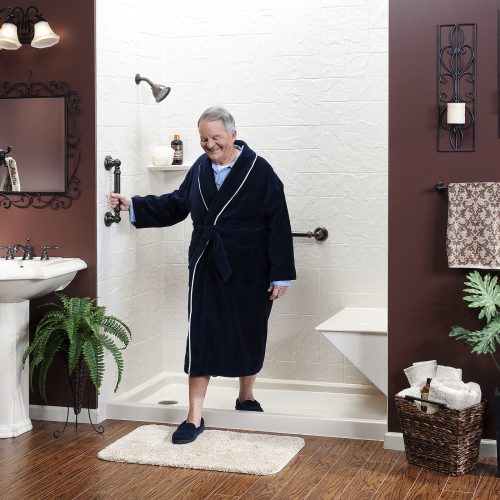A man confidently steps out of a stylish walk-in shower in a red-themed bathroom. Equipped with grab bars, shower seat, and more, installed by Atlas Home Safety.