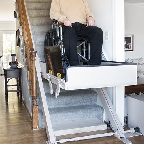 man on a incline platform lift installed on his home's staircase